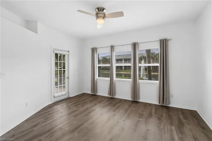 Unfurnished room featuring ceiling fan, dark wood-type flooring, and a wealth of natural light