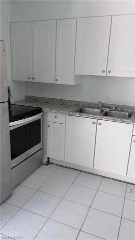 Kitchen featuring stainless steel appliances, white cabinetry, and light tile patterned floors