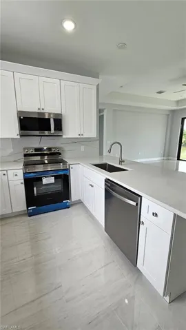 Kitchen with tasteful backsplash, light tile flooring, sink, white cabinetry, and appliances with stainless steel finishes