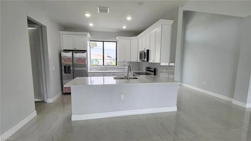 Kitchen featuring stainless steel appliances, tasteful backsplash, white cabinets, sink, and light tile floors
