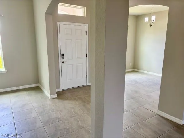 Tiled entryway with an arched doorway leading to an additional space