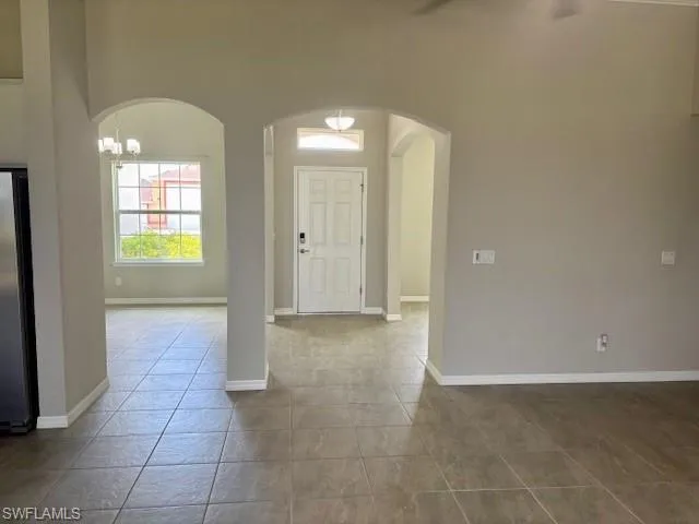 Spacious interior featuring a front entry door with transom window, arched doorways, tile flooring, and a contemporary ceiling fan