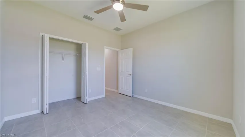 This room features tiled flooring, light-colored walls, and a ceiling fan with integrated lighting
