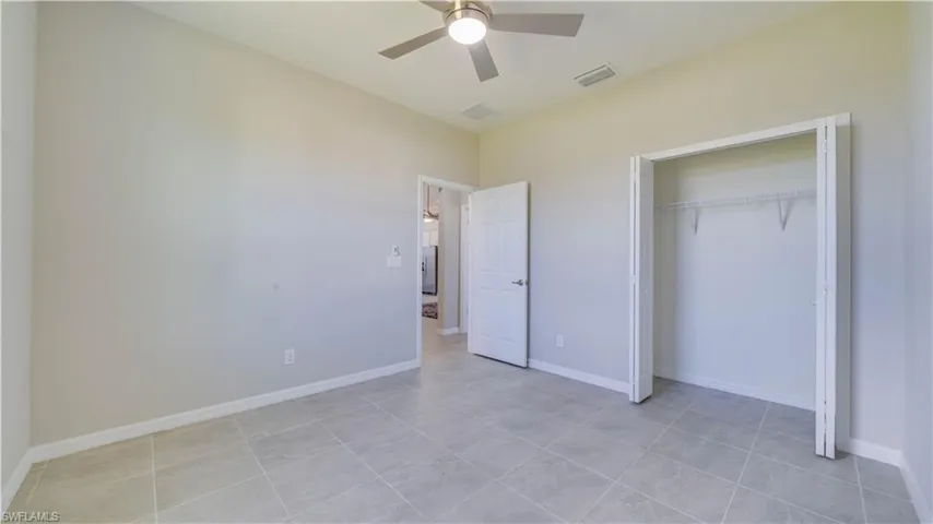This bright room features tile flooring, light-colored walls, and a ceiling fan