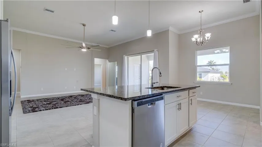 The kitchen features a center island with a granite countertop and a stainless steel dishwasher