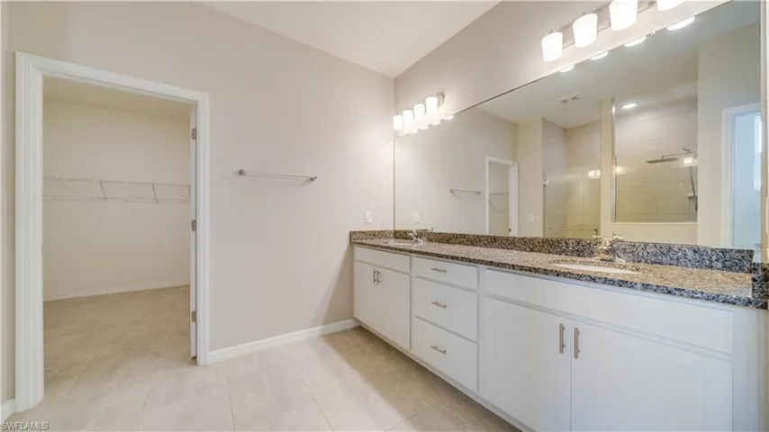 The bathroom features a long vanity with dual sinks, a granite countertop, and ample storage cabinetry