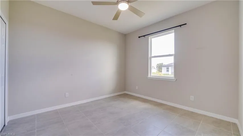 Guest Bedroom features light-colored tile flooring, a window providing natural light, and a ceiling fan