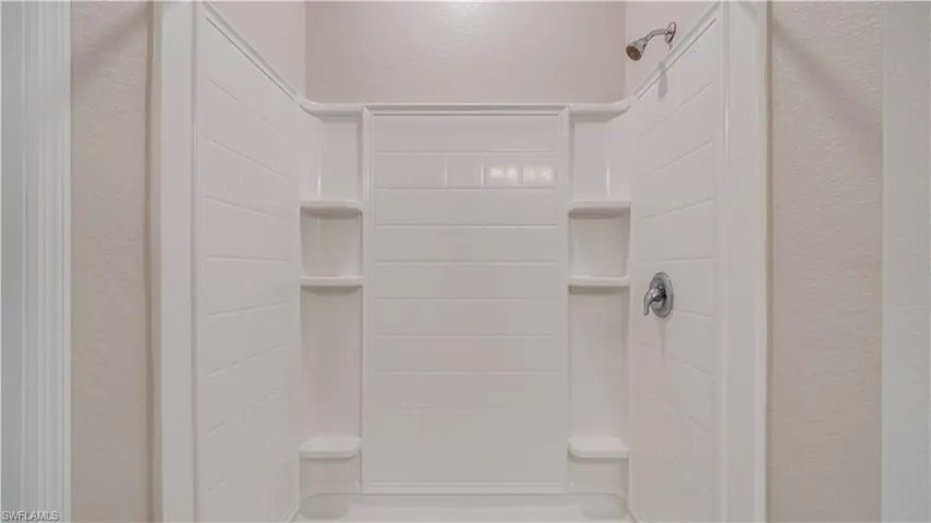 Shower in Cabana Bathroom with a white tiled surround, integrated shelving.