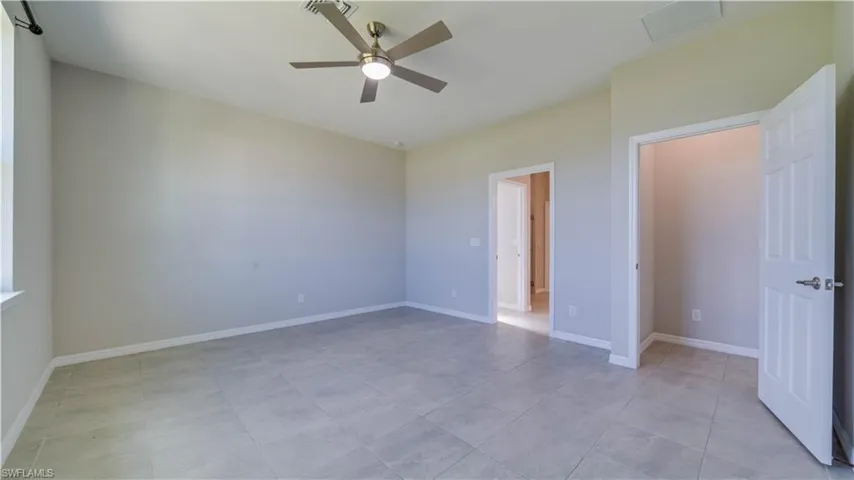 This room features light-colored tile flooring, neutral wall paint, and a ceiling fan with integrated lighting
