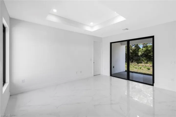 Spare room featuring recessed lighting, a tray ceiling, and light marble finish floors