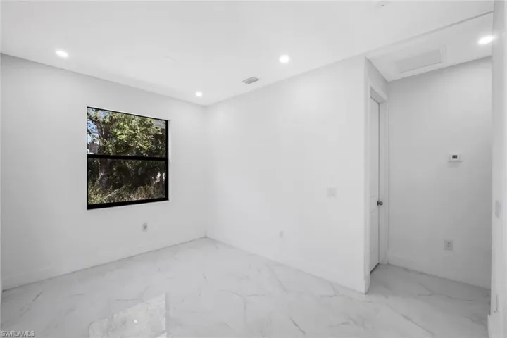 Empty room with light marble finish floors and recessed lighting