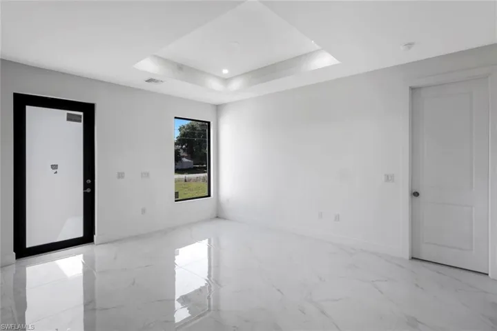 Empty room featuring light marble finish floors, a tray ceiling, and recessed lighting