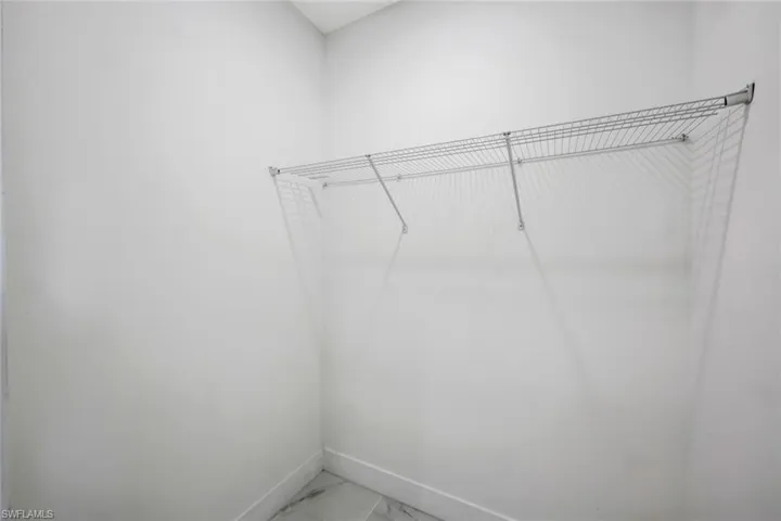 Walk in closet featuring light marble finish flooring