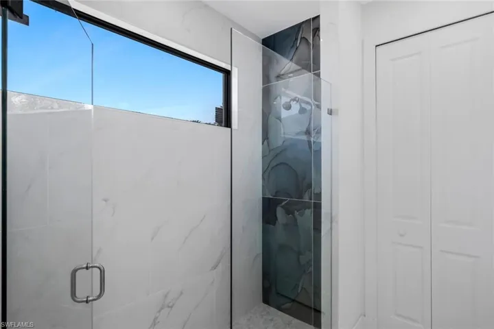 Full bathroom with a marble finish shower and a closet