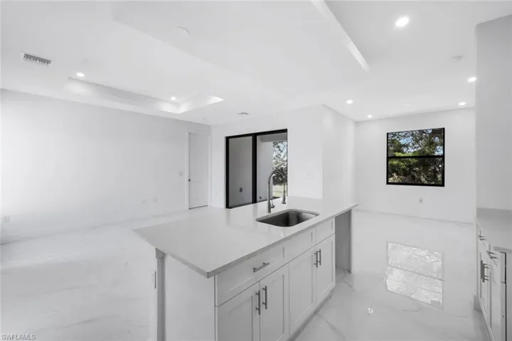 Kitchen with a center island with sink, light marble finish floors, plenty of natural light, light stone countertops, and recessed lighting