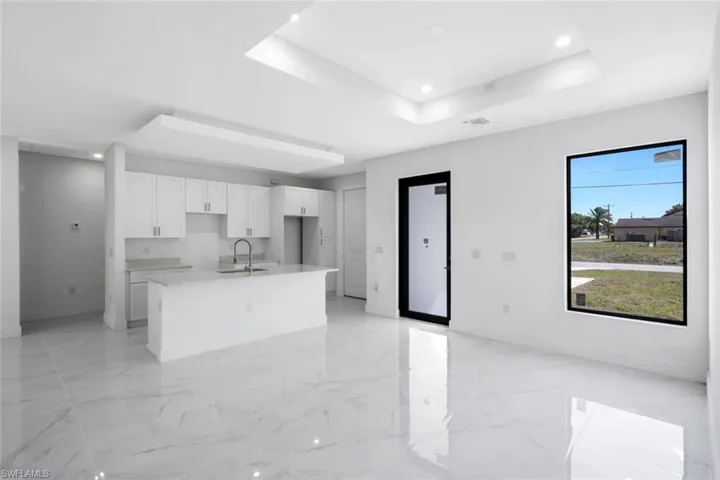 Kitchen featuring white cabinetry, a kitchen island with sink, recessed lighting, a raised ceiling, and open floor plan