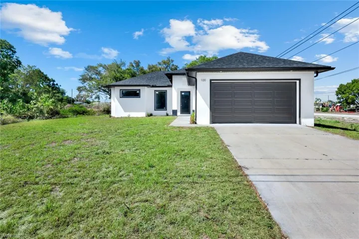 Single story home featuring stucco siding, a garage, a front lawn, driveway, and roof with shingles