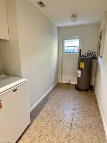 Laundry area with light tile patterned flooring, washer / clothes dryer, and water heater