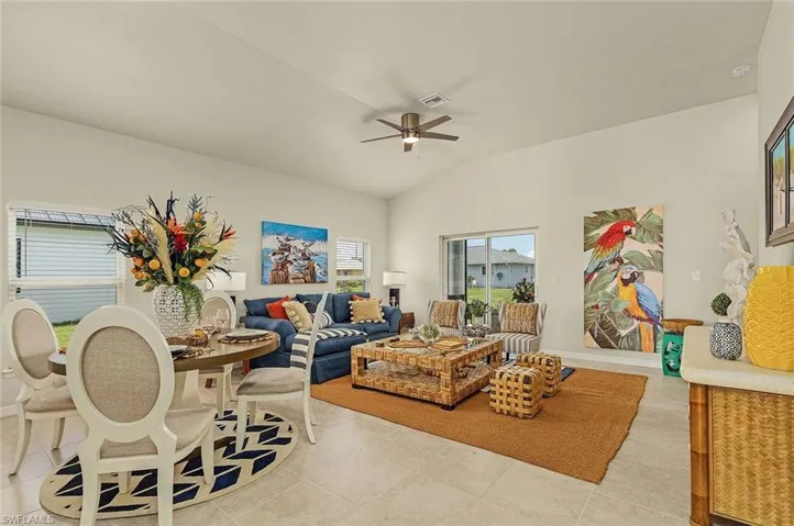 Living room featuring lofted ceiling, ceiling fan, and light tile patterned flooring