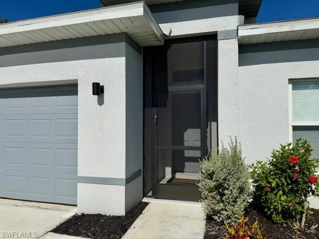 Property entrance with a garage and stucco siding