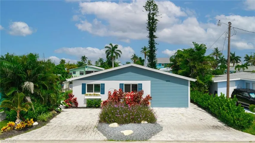 White exterior with blue siding accents, covered front entry, and a paved driveway