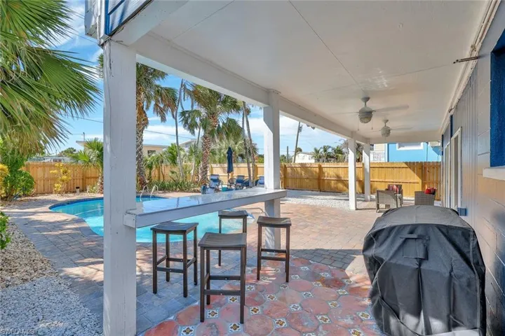 View of patio / terrace featuring a fenced in pool, grilling area, ceiling fan, and an outdoor bar