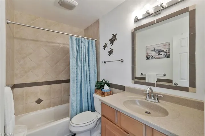 Full bathroom with vanity, shower / bath combo, and toilet