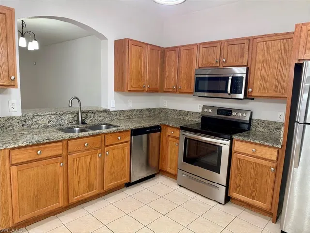 Kitchen featuring stainless steel appliances, dark stone counters, and brown cabinetry
