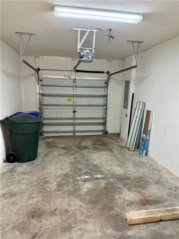 Garage featuring a textured wall, electric panel, and a garage door opener