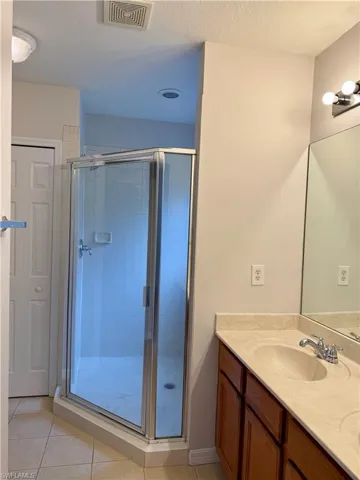 Full bathroom featuring double vanity, a stall shower, light tile patterned floors, and a textured ceiling