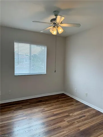 Spare room featuring dark wood finished floors and ceiling fan