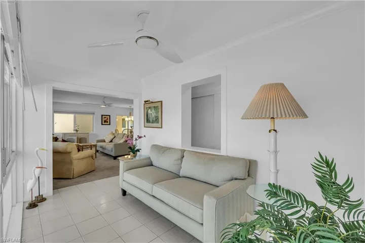 Tiled living area with ornamental molding, carpet flooring, and a ceiling fan