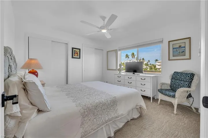 Bedroom with two closets, a ceiling fan, and light carpet
