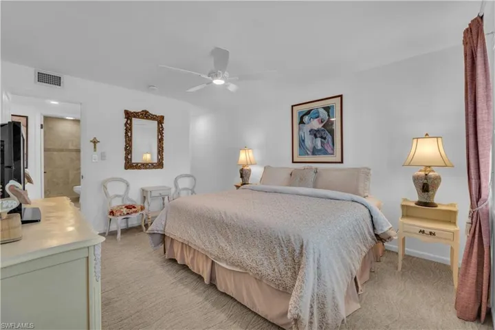Bedroom with light carpet, a ceiling fan, and connected bathroom