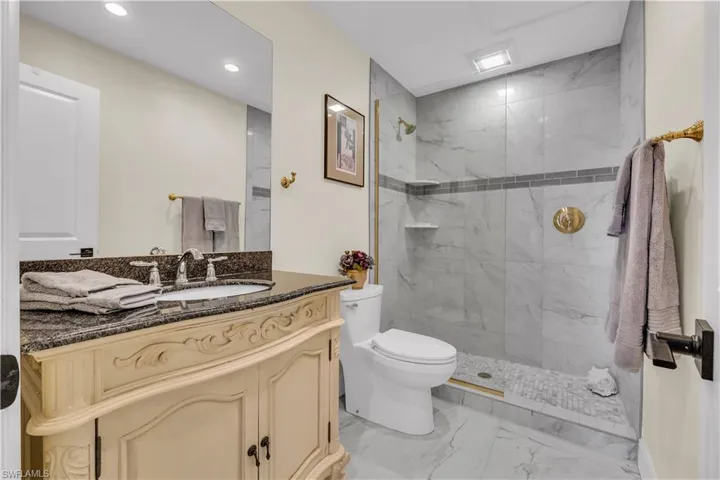 Bathroom with vanity, light marble finish flooring, a marble finish shower, and recessed lighting