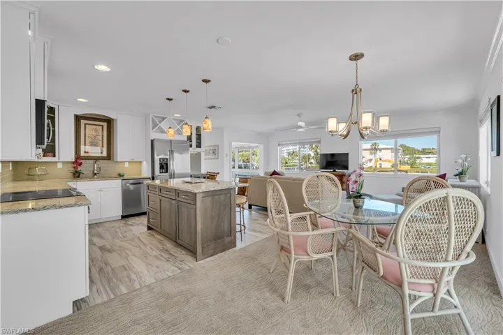 Kitchen featuring ceiling fan, white cabinets, glass insert cabinets, light stone countertops, and hanging light fixtures