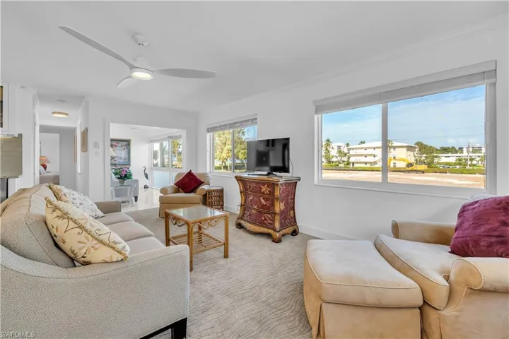 Living area with a ceiling fan, crown molding, and carpet floors
