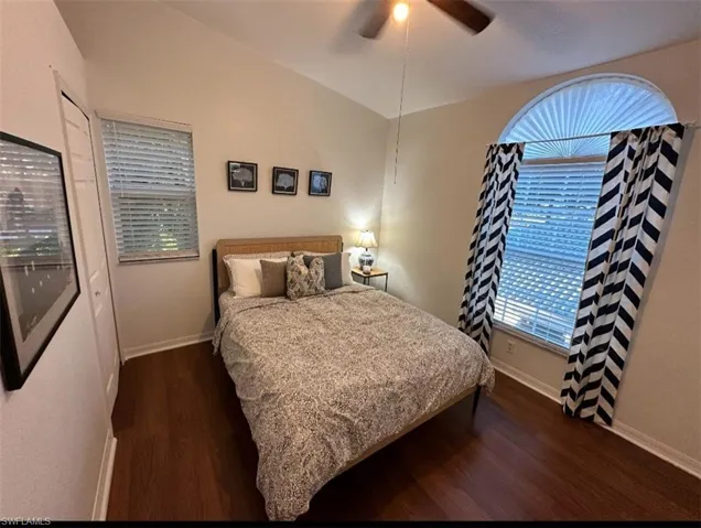 Bedroom with lofted ceiling, dark wood-style floors, a closet, and ceiling fan