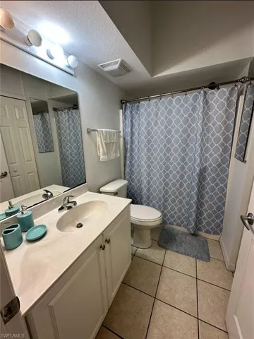 Bathroom with a textured ceiling, vanity, light tile patterned flooring, and a shower with curtain