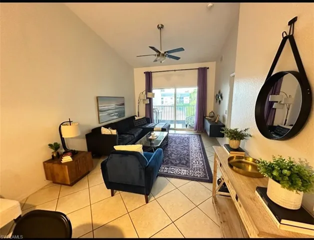 Living room featuring light tile patterned floors, ceiling fan, and lofted ceiling