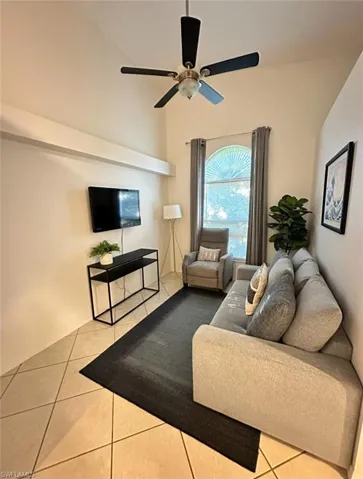 Living room featuring light tile patterned floors, ceiling fan, and a towering ceiling