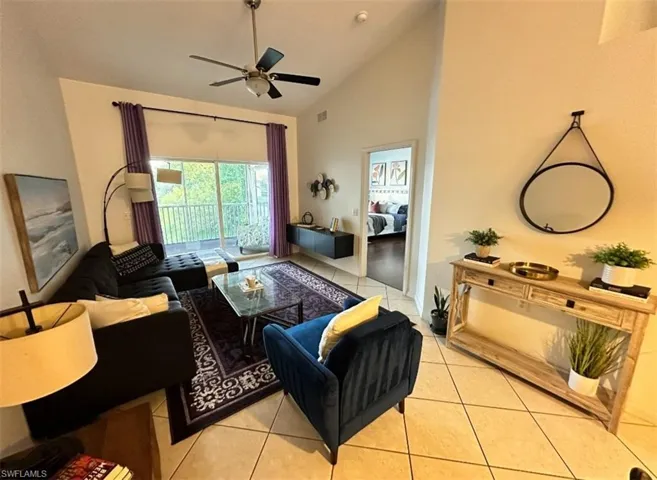 Living room with light tile patterned floors, high vaulted ceiling, and ceiling fan