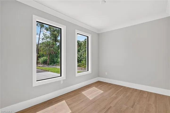 Neutral wall tones, wood-finish flooring, and dual picture windows with black frames