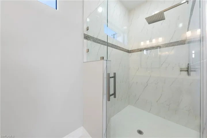 Full bathroom featuring a marble finish shower and baseboards