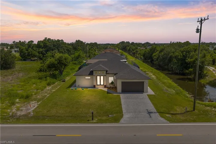 View of front facade with decorative driveway, a front lawn, a garage, stucco siding, and a shingled roof