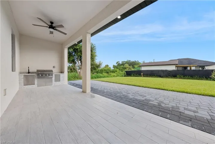 Wooden terrace with area for grilling, ceiling fan, and a patio area
