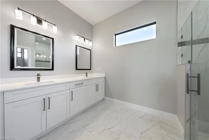 Bathroom with marble finish flooring, double vanity, and a marble finish shower