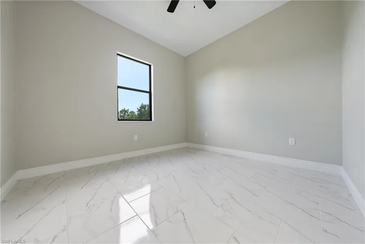 Empty room with light marble finish floors, a ceiling fan, and lofted ceiling