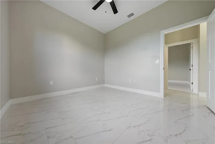 Spare room with light marble finish floors and a ceiling fan