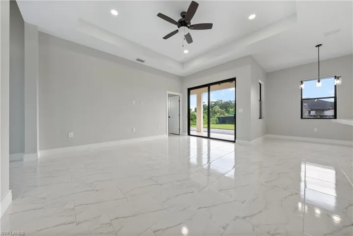 Unfurnished room featuring light marble finish floors, a tray ceiling, a ceiling fan, and recessed lighting